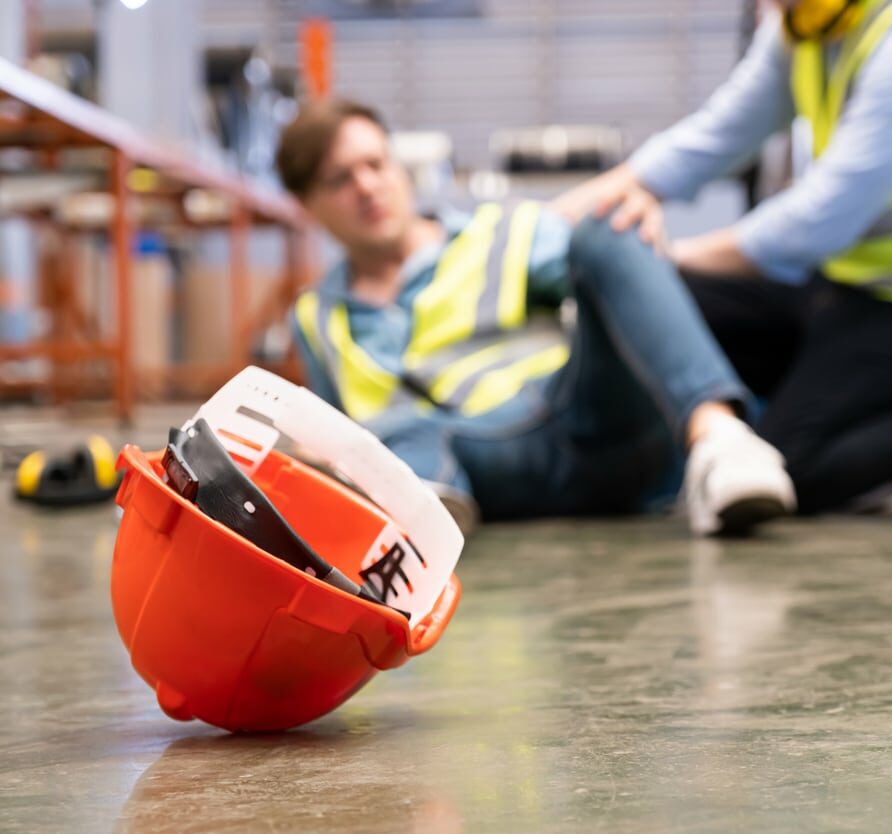 Selective focus at hat, Men worker feel painful and hurt from the accident that happen inside of industrial factory while his co-worker come to give emergency assistance and help. Accident in factory.